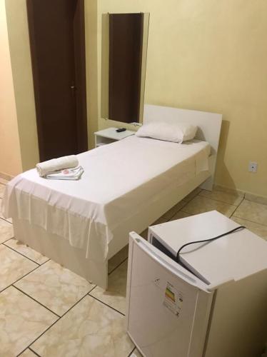 a bedroom with a white bed and a refrigerator at Hotel Dom Alcides in Nova Santa Medianeira