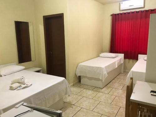 a room with two beds and a red curtain at Hotel Dom Alcides in Nova Santa Medianeira