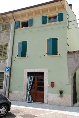 a white building with blue shutters and a door at La casa dei ciclisti in Ponti Sul Mincio