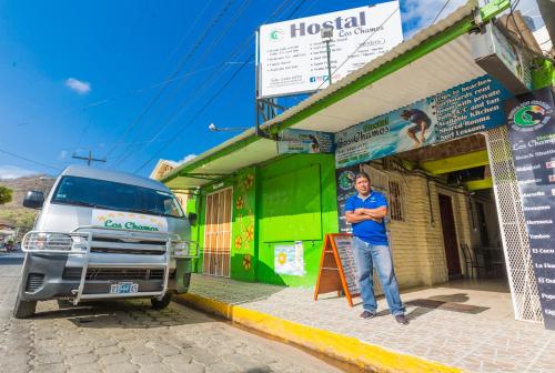 a man standing in front of a building next to a truck at Hostal Los Chamos in San Juan del Sur