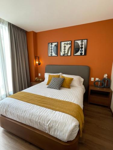 a bedroom with a large bed with orange walls at Condesa Cibel in Mexico City
