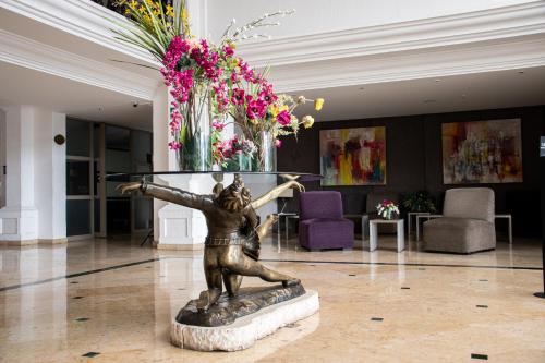 a statue of a woman in a lobby with flowers at Hotel Victoria Express in Durango