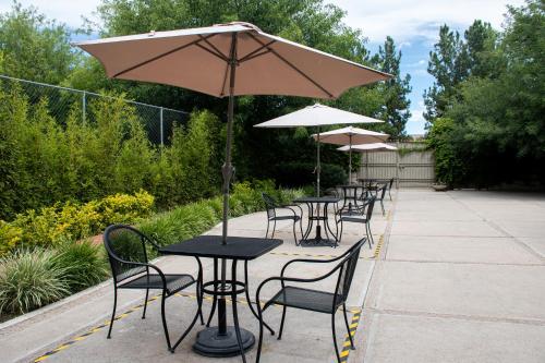 a row of tables and chairs with an umbrella at Hotel Victoria Express in Durango