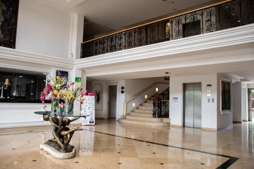 a lobby with a vase of flowers and stairs at Hotel Victoria Express in Durango