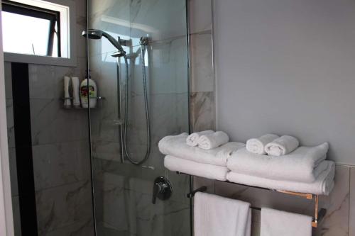 a bathroom with a shower with towels on a rack at Poppy Apartment in Coromandel Town
