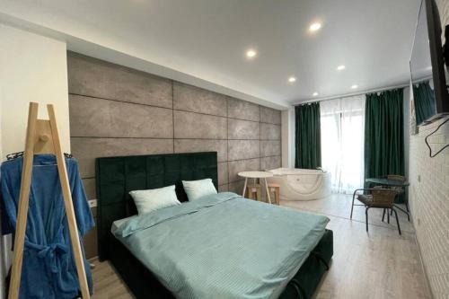 a bedroom with a bed and a bathroom with a tub at Arkadiya Sky Jakuzi & MP 25 in Odesa