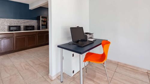 a desk with a computer and a orange chair at SureStay Hotel By Best Western Olathe in Olathe
