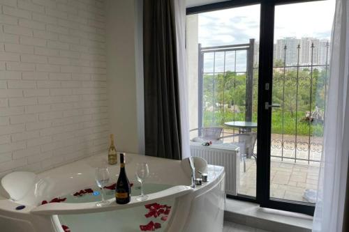 a bath tub with two wine glasses and a window at Arkadiya Sky Jakuzi & Angelika 23 in Odesa