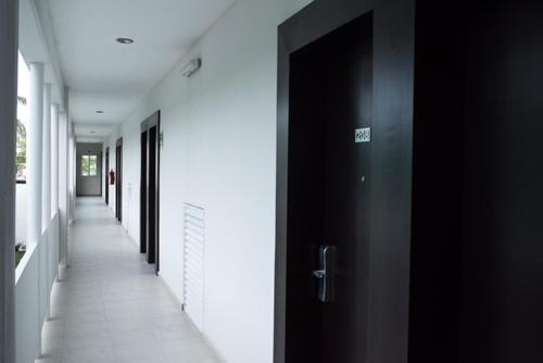 an empty hallway with black doors and white walls at Hotel Noor in Chetumal