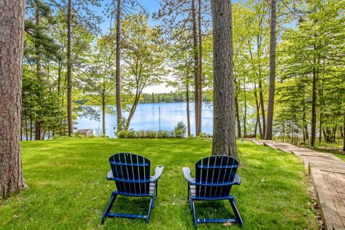 two blue chairs sitting in the grass near a lake at Road Lake Escape in Tomahawk