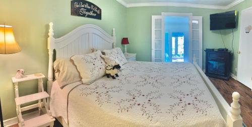 a bedroom with a white bed with a teddy bear on it at Lamb's Rest Inn in New Braunfels