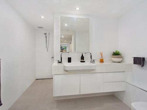 uma casa de banho branca com um lavatório e um espelho em The Rocks Resort Apartment GE em Gold Coast