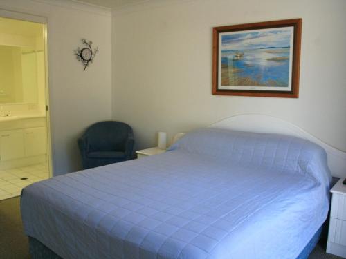1 dormitorio con 1 cama azul y 1 silla en Riverview Unit 6 en Gold Coast