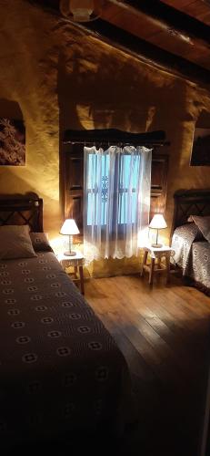 a bedroom with two beds and a window with two lamps at Casa rural El Patio con chimenea, barbacoa, piscina, patios exteriores para sus mascotas de manera gratuita in Benadalid