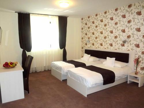 a bedroom with two beds and a floral wallpaper at West Plaza Residence in Bucharest