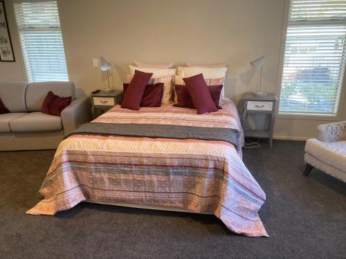 a bedroom with a bed and a couch and windows at Cambridge Te Awa Rivertrail BnB in Cambridge