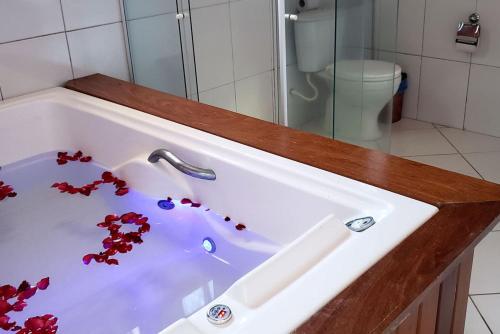 a white bath tub with red flowers in it at Pousada Kairos & Spa em Búzios in Búzios