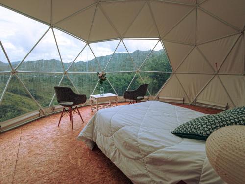 a room with a bed and chairs in a tent at VíaLáctea Glamping in Loja