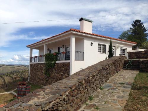 a white house with a stone wall at Quinta dos Espinheiros in Provesende