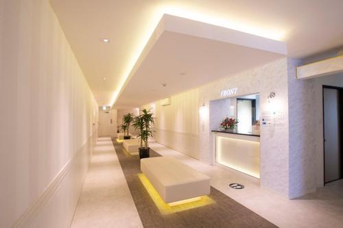 een lobby van een gebouw met een bank en een tafel bij HOTEL xcell in Fukuyama