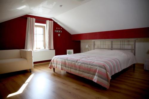 una camera rossa con letto e divano di Une parenthèse en Ardenne a Nollevaux
