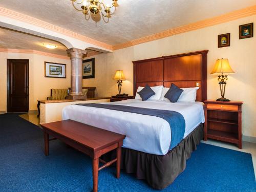 una habitación de hotel con una cama grande y una mesa en Quinta del Rey Hotel en Toluca
