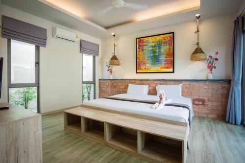 a bedroom with a large bed with a wooden bench at Yipmunta Pool Villa - SHA Plus Certified in Bang Tao Beach