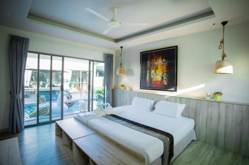 a bedroom with a large white bed and a balcony at Yipmunta Pool Villa - SHA Plus Certified in Bang Tao Beach