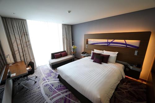 a hotel room with a large bed and a chair at Novotel Ambassador Suwon in Suwon