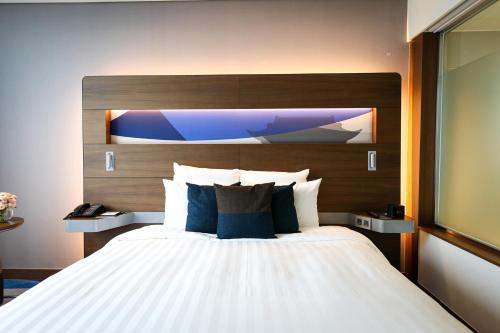 a bedroom with a large bed with a wooden headboard at Novotel Ambassador Suwon in Suwon