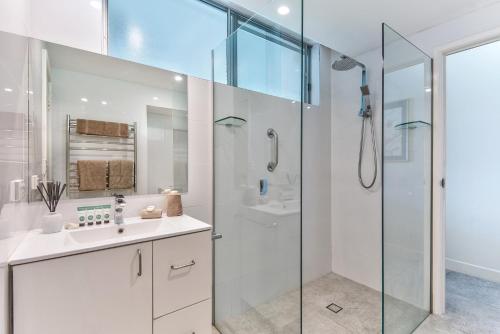 a white bathroom with a shower and a sink at Whitsunday East 1106 on Hamilton Island by HamoRent in Hamilton Island