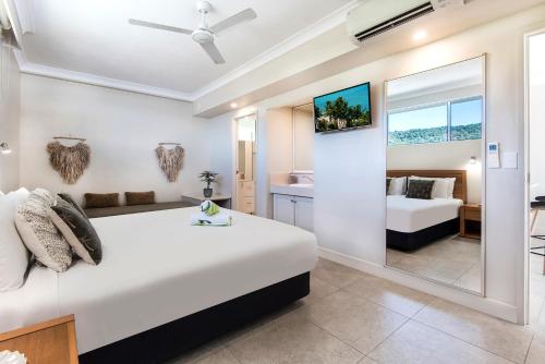 a bedroom with a large white bed and a mirror at Whitsunday East 1106 on Hamilton Island by HamoRent in Hamilton Island