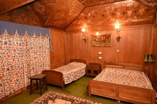 two beds in a room with wooden walls at Kings Houseboats in Srinagar