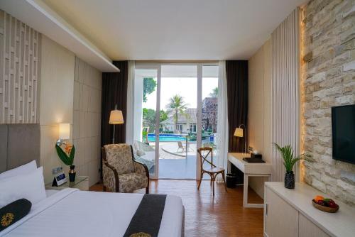 a hotel room with a bed and a desk and a tv at Java Heritage Hotel Purwokerto in Purwokerto