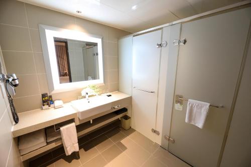 a bathroom with a sink and a mirror and a shower at Novotel Ambassador Suwon in Suwon