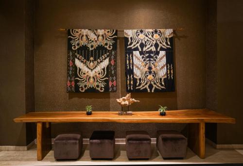 a wooden table with chairs in a room with curtains at Java Heritage Hotel Purwokerto in Purwokerto
