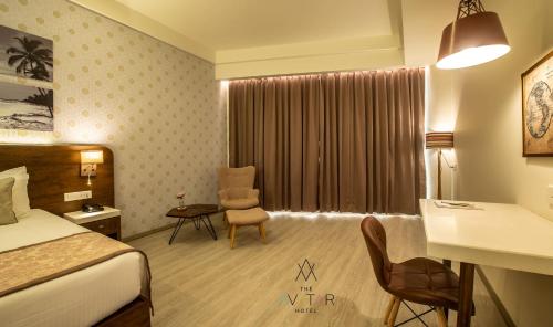 a hotel room with a bed and a desk and chair at The Avatar Hotel & Convention in Mangalore