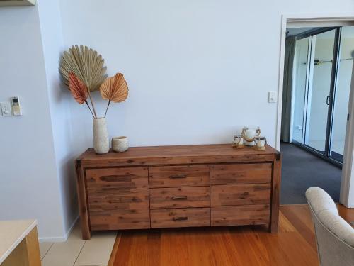 a wooden dresser with a vase on top of it at Azure Sea Whitsunday Resort in Airlie Beach