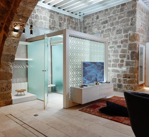 a bathroom with a glass shower and a television at Dalaa in ‘Akko