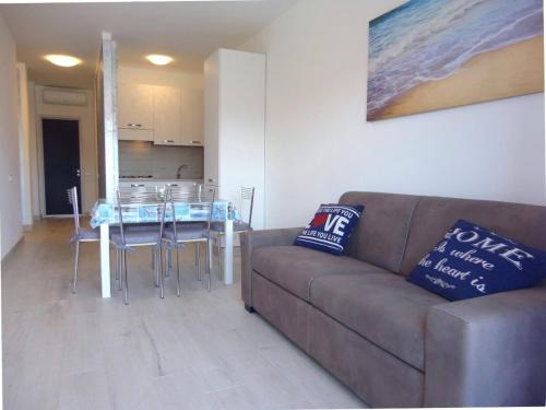 uma sala de estar com um sofá e uma mesa com cadeiras em Modern flat for 6 with shared pool em Porto Santa Margherita di Caorle