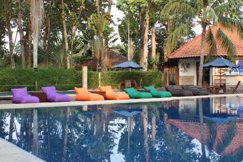 a pool with colorful chairs next to a house at Sanghyang Indah Spa Resort in Anyer