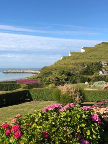 a garden with flowers and a view of the ocean at Le Chalet Caux-Marin in Tourville-la-Chapelle
