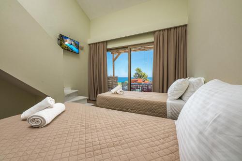 a hotel room with two beds and a view of the ocean at Kozanos Suites with Private Pool in Amoudi