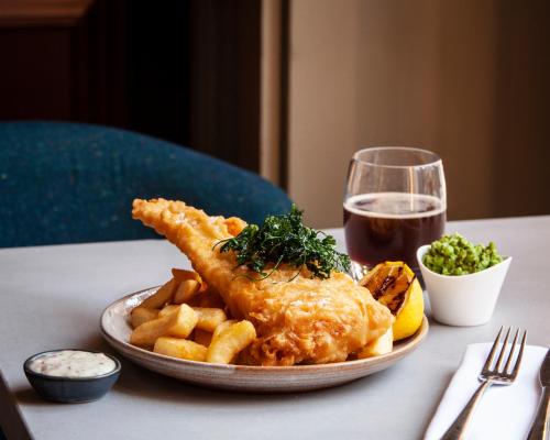 a plate of fish and french fries and a glass of wine at The Clermont London, Victoria in London
