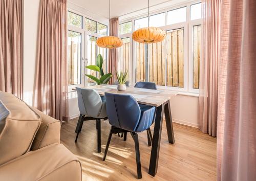 a dining room with a table and chairs and windows at Boutique resort Schaardijk 13 in Scharendijke