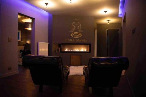 a living room with a fireplace and two chairs at El nido Malaika-Villa privative in Monts