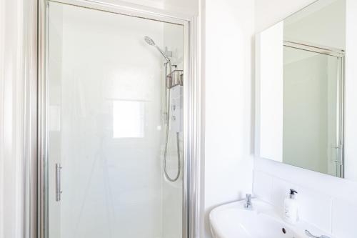 a bathroom with a shower and a sink and a mirror at Fern Lodge 11 with Hot Tub in Belladrum