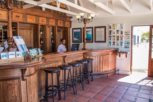 a man standing at a bar in a restaurant at Harbour House Hotel - Harbour Square in Hermanus
