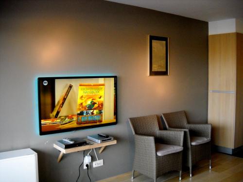 Habitación con 2 sillas y TV de pantalla plana en la pared. en Lautrec en Bredene
