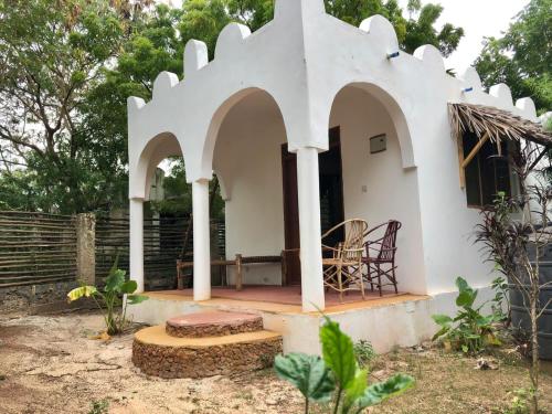 a small white house with a table and chairs at Magharibi House in Nungwi